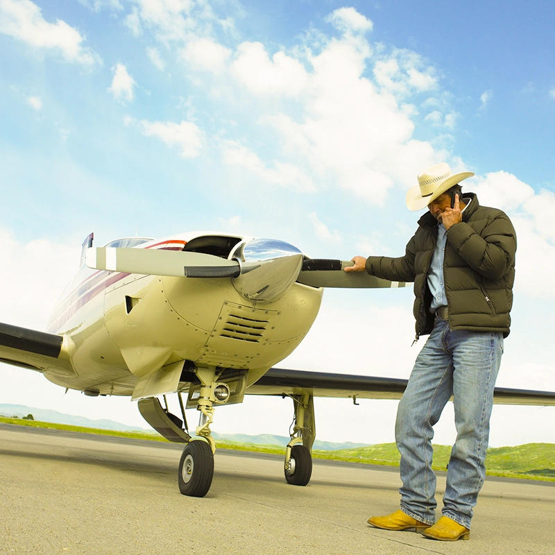 Man talking on mobile phone in front of Bonanza plane